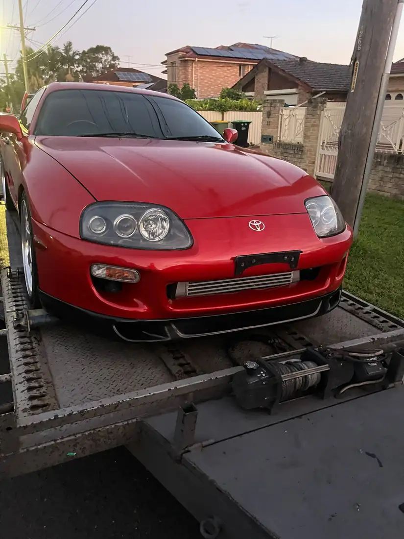 Red classic Toyota Supra on a trailer after collection