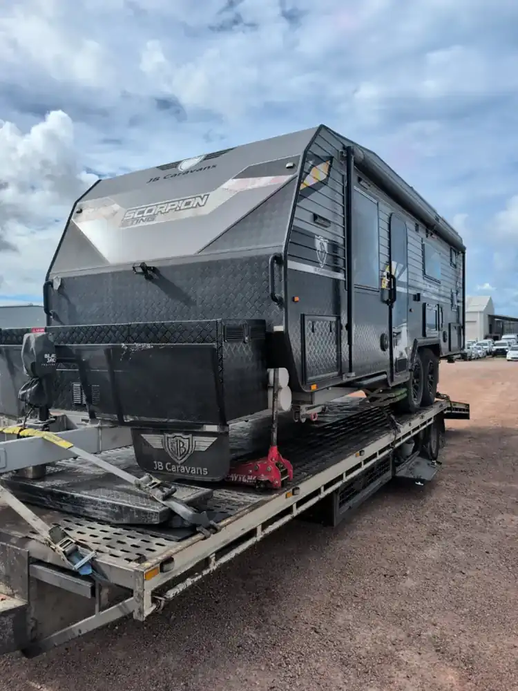 Off-road caravan strapped to a car trailer for cartage to the port