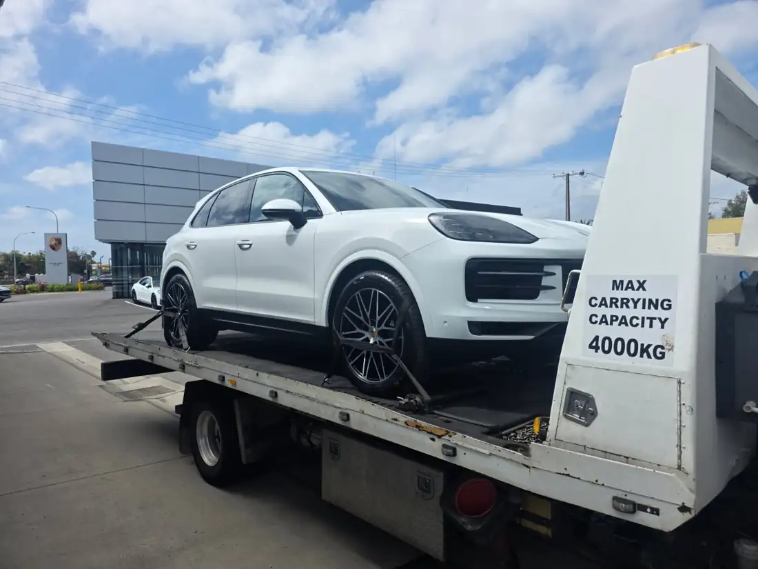 White Porsche Cayenne collected from a dealership on a tilt-tray truck
